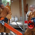 Ajahn Ñaniko and Ajahn Sek inspect the chainsaw as Sāmaṇera Cittapālo looks on.