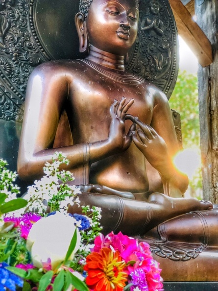 The Buddha Image at the monastery's outdoor meditation platform, honored at sunset with bouquets of flowers.