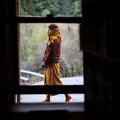 A sāmaṇera bundles up against the cold as he does walking meditaiton outside the library window.