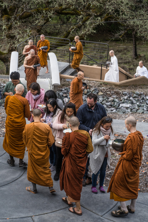 Lay supporters distributing rice to monks during the ceremonial alms round