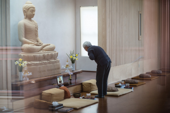 Jeed pauses to pay homage to the Buddharupa while arranging flowers in the Dhamma hall. 