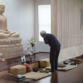 Jeed pauses to pay homage to the Buddharupa while arranging flowers in the Dhamma hall. 