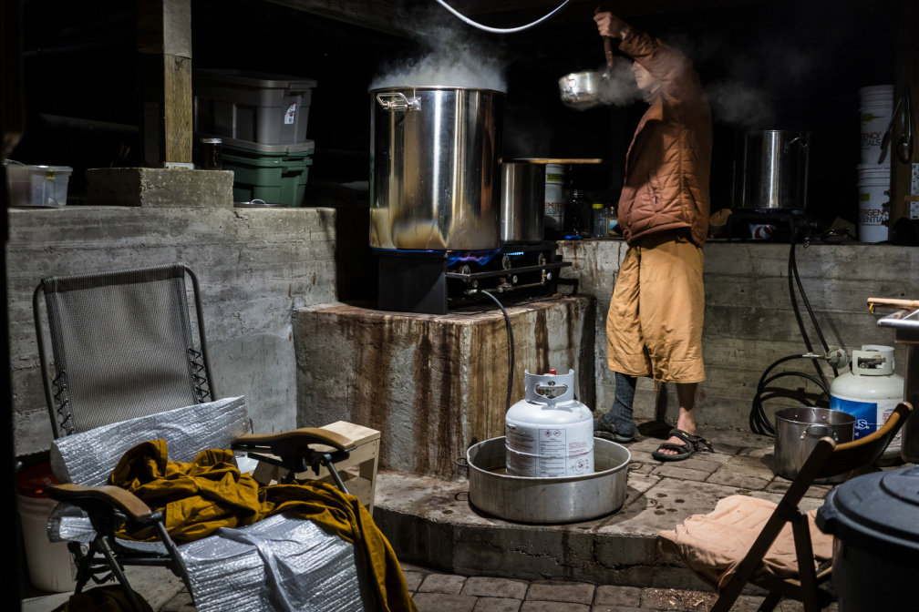 After straining the madrone bark, Dhammavavro moves the weak dye liquid to another pot, where it will be boiled and reduced. To stay on schedule, he spent four nights' vigil in a cold basement retrofitted with dyeing equipment.