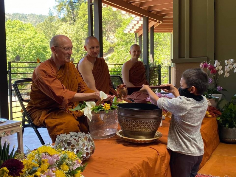 Luang Por has his hands cleansed by a visitor
